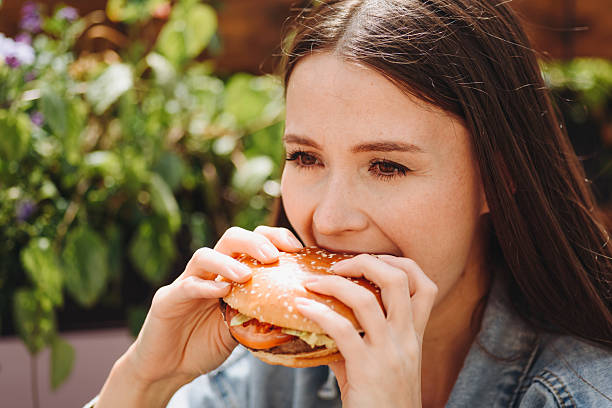 istock hamburger in hands, closeup view, young woman eats hamburger 2238426027