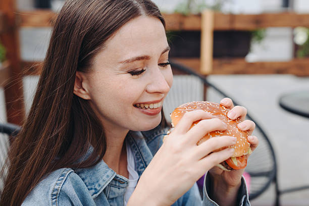istock hamburger in hands, closeup view, young woman eats hamburger 2238426039