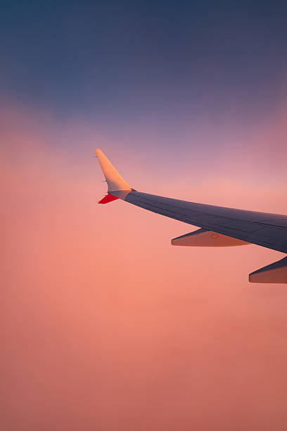 istock Plane wing among pink clouds at sunset 2238428627