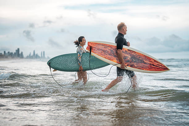 istock Energetic Surfing Couple Running into Gold Coast Waves 2238429473