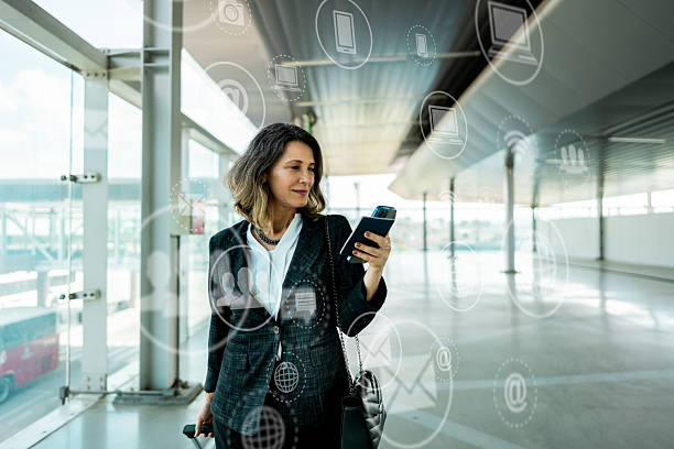 istock Mature businesswoman walking while using the mobile phone with futuristic digital technology interface at the airport 2238430224