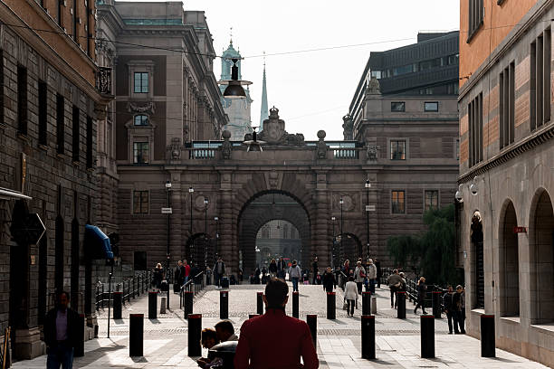Stockholm, Sweden - September 22, 2014 - Cobbled pathway leading to historic stone arch in bustling urban square.