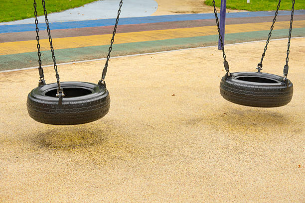 two tire swings hang quietly in a colorful park