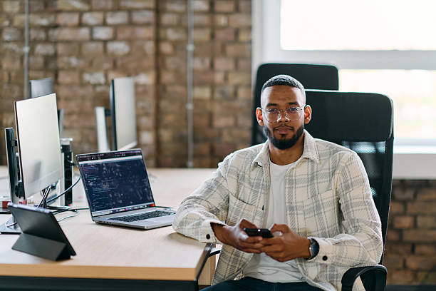 istock African American entrepreneur takes a break in a modern office, using a smartphone to browse social media, capturing a moment of digital connectivity and relaxation amidst his business endeavors. 2238447830