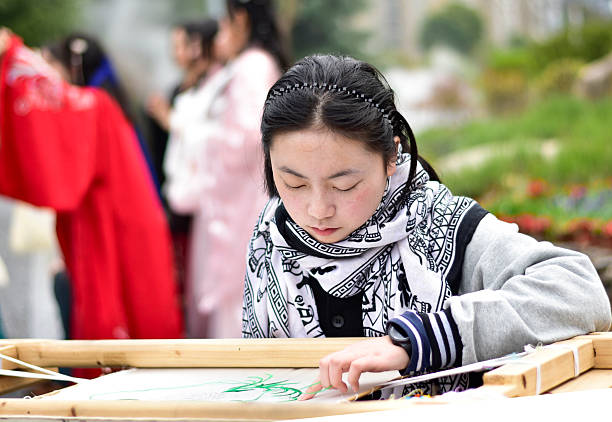 Wuhan, China - A young girl works carefully on traditional embroidery during a cultural activity on March 23, 2019. The photo highlights the preservation of handicraft skills and cultural heritage in the modern city.