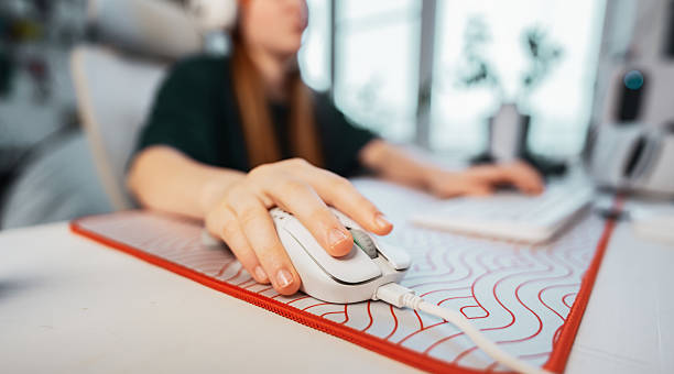 A focused woman skillfully navigates her workspace using a computer mouse, showcasing modern technology