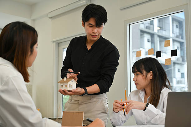 istock Young architect presenting a miniature house model to colleagues during a project meeting in a modern office 2238458561