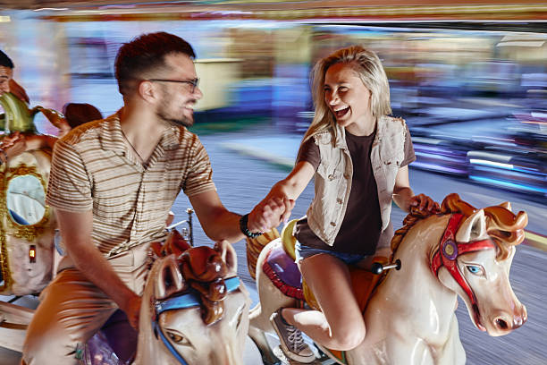 istock Carefree couple talking during a ride at amusement park in blurred motion. 2238466399