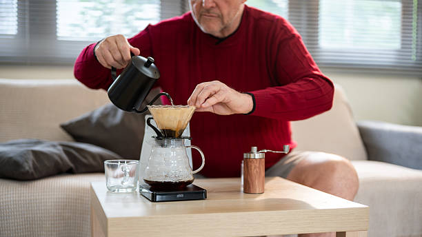 istock Old white caucasian man using kettle pouring hot water into coffee in filter paper on the dripper. 2238469353