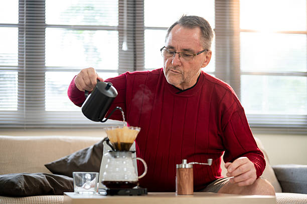istock Glasses old white man using kettle pouring hot water into coffee in filter paper on dripper at table 2238469356
