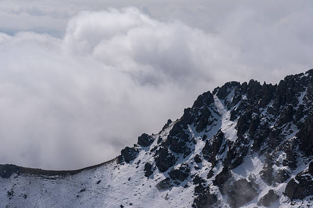 istock Snow-dusted alpine mountain range shrouded in fog and clouds 2238470509
