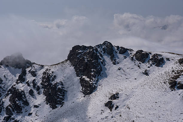 istock Snow-dusted alpine mountain range shrouded in fog and clouds 2238470579