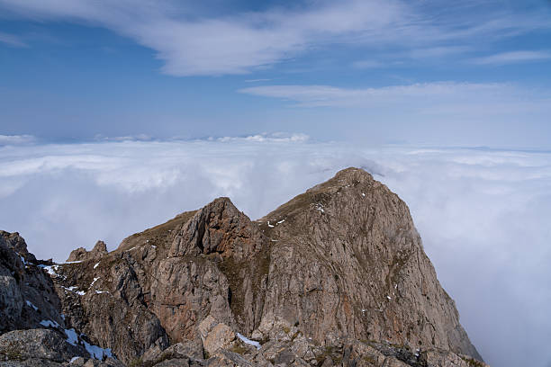 istock Snow-dusted alpine mountain range shrouded in fog and clouds 2238471265