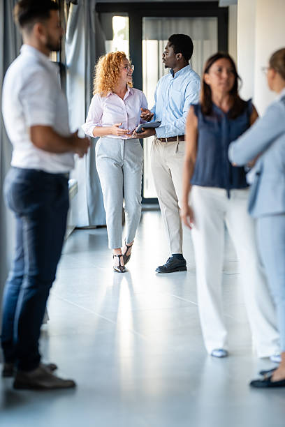 istock Business professionals networking and discussing ideas in modern office hallway 2238471982