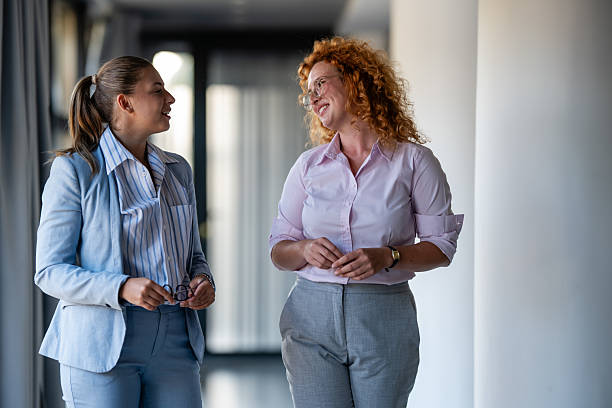 istock Professional businesswomen having friendly conversation in modern office hallway 2238473816