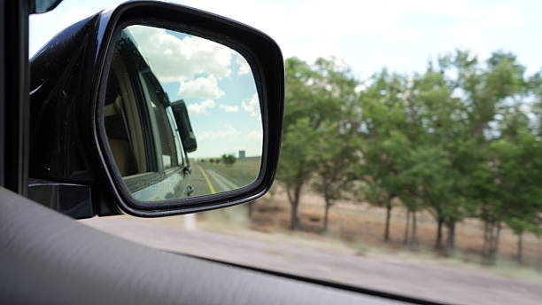 istock Car side mirror reflecting road and sky during road trip 2238479712
