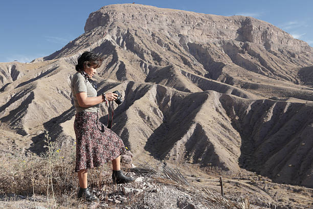 Woman explorer reviewing camera on desert mountain