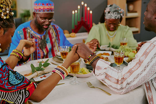 istock Black Family Holding Hands and Praying during Kwanzaa Celebration Dinner 2238481890