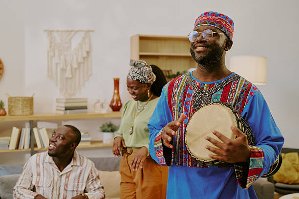 istock Young Black Man Playing Drum While Friends Celebrate Kwanzaa Indoors 2238482560