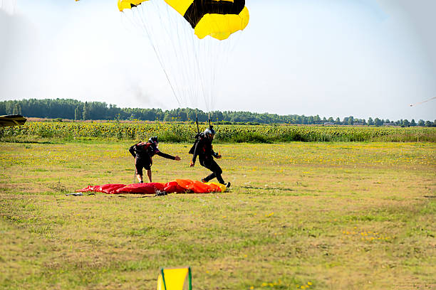 istock Skydiver and instructor tandem landing on open field with colorful canopy under clear sky 2238486359