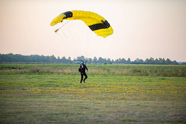 istock Skydive enthusiast lands softly on a green field beneath a bright yellow canopy 2238486704