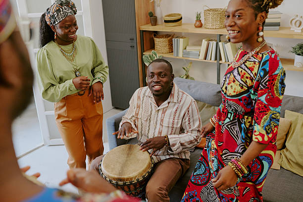 istock Young Black Man Playing Drum Surrounded by Smiling Young Black Women Celebrating Kwanzaa 2238486777