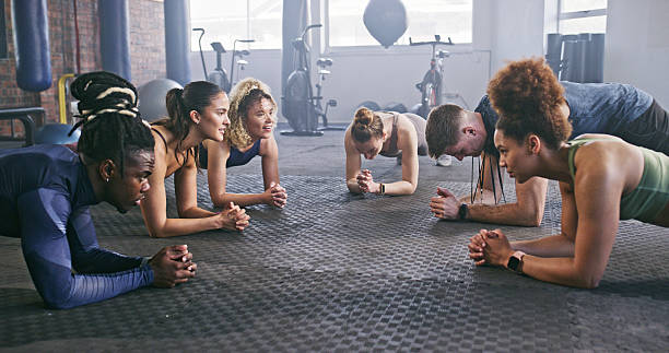 istock Group Fitness Training Session With People Doing Planks in a Gym 2238487426