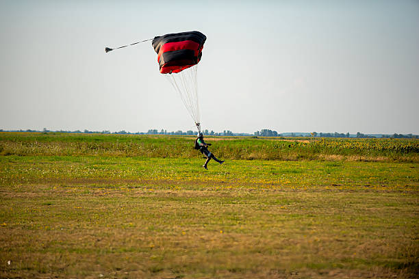 istock Skydiver with colorful parachute gliding toward a green field for a controlled landing 2238487581