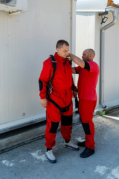 istock Experienced skydiving instructor fits and checks safety harness on student before tandem jump 2238487715