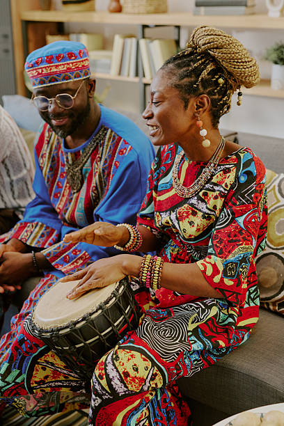 istock Young Black Woman Playing Drum Beside Young Black Man during Kwanzaa Celebration 2238490009