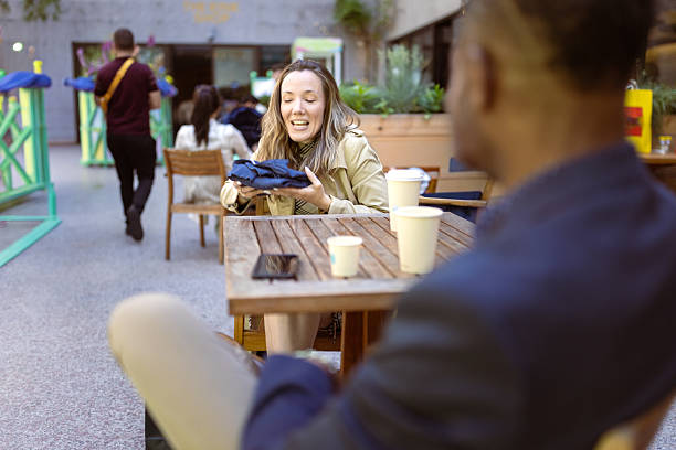 Woman with a cafe latte smiles at her male companion.