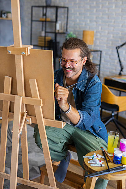 istock Creative man painting artwork on canvas in a modern apartment filled with natural light 2238493220