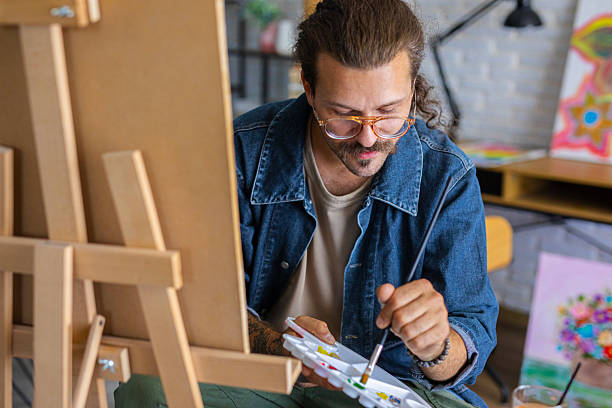 istock Creative man painting artwork on canvas in a modern apartment filled with natural light 2238493279