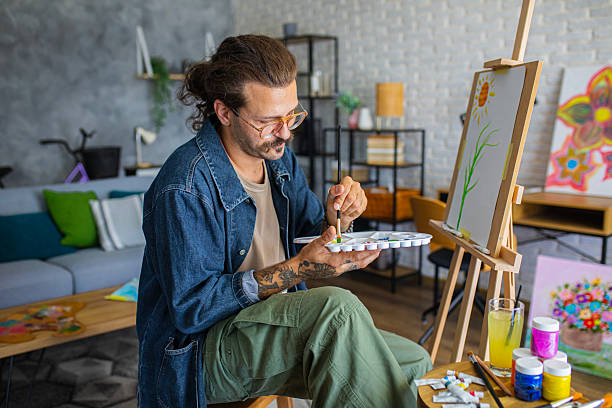 istock Creative man painting artwork on canvas in a modern apartment filled with natural light 2238494085