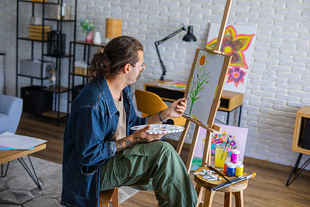 istock Creative man painting artwork on canvas in a modern apartment filled with natural light 2238495502
