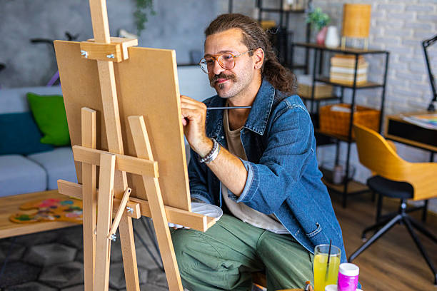 istock Creative man painting artwork on canvas in a modern apartment filled with natural light 2238495659