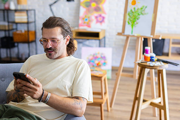 istock Artist using a smartphone to search for inspiration while preparing to draw on canvas in his home studio 2238496068