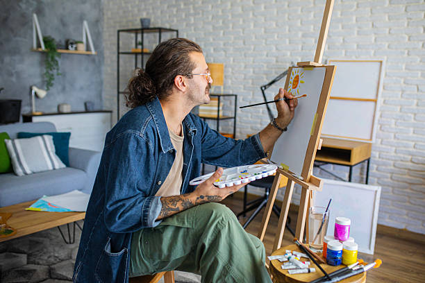 istock Creative man painting artwork on canvas in a modern apartment filled with natural light 2238496857