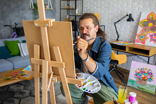 istock Creative man painting artwork on canvas in a modern apartment filled with natural light 2238497021
