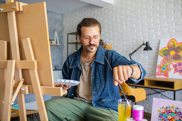 istock Creative man painting artwork on canvas in a modern apartment filled with natural light 2238497091