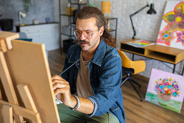 istock Creative man painting artwork on canvas in a modern apartment filled with natural light 2238497182