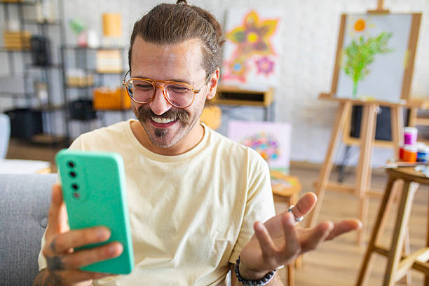 istock Young artist having a video call on his smartphone while sitting in his home studio 2238497279