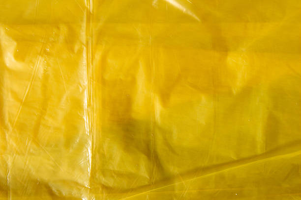 istock Bright yellow plastic wrap sheet surface with creases and folds 2238500121