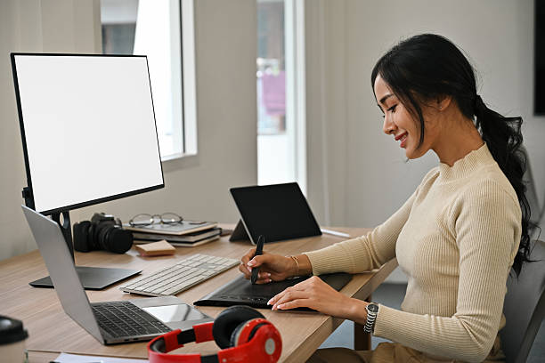 istock A Young female graphic designer using a digital drawing tablet and stylus pen in a bright modern office. Creative professional working on design projects 2238500247