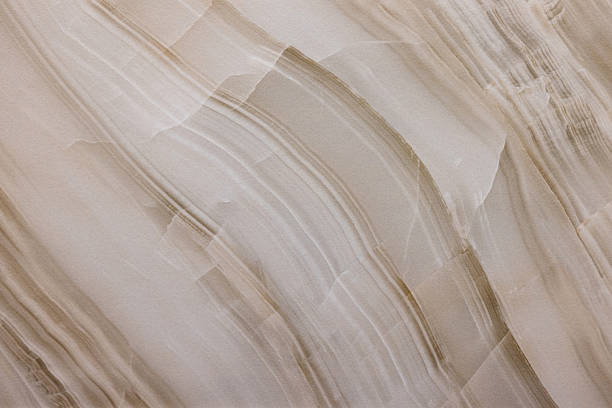 Closeup of a beige marble surface featuring flowing layers and gentle curves. Neutral tones and organic patterns create a calm, versatile background suitable for design, editorial, or product visuals.