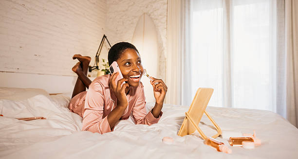 istock Woman using facial roller having phone call in bed 2238509538