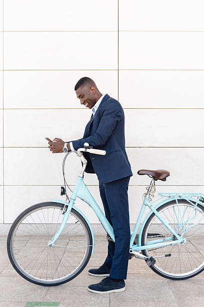 istock African american businessman using mobile phone while standing with bicycle against a white wall 2238512936