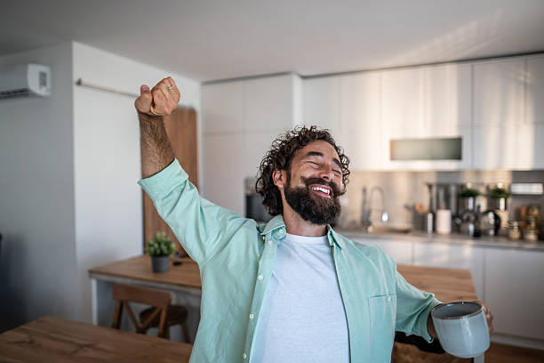 istock Happy man stretching in kitchen holding coffee mug 2238513221