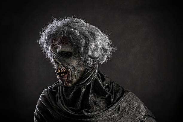 Scary zombie with gray hair over dark background