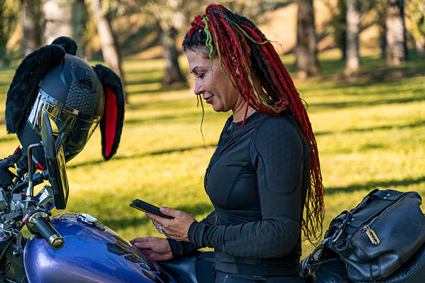 istock Woman biker with colorful dreadlocks sitting on a motorcycle and using a smartphone 2238515374